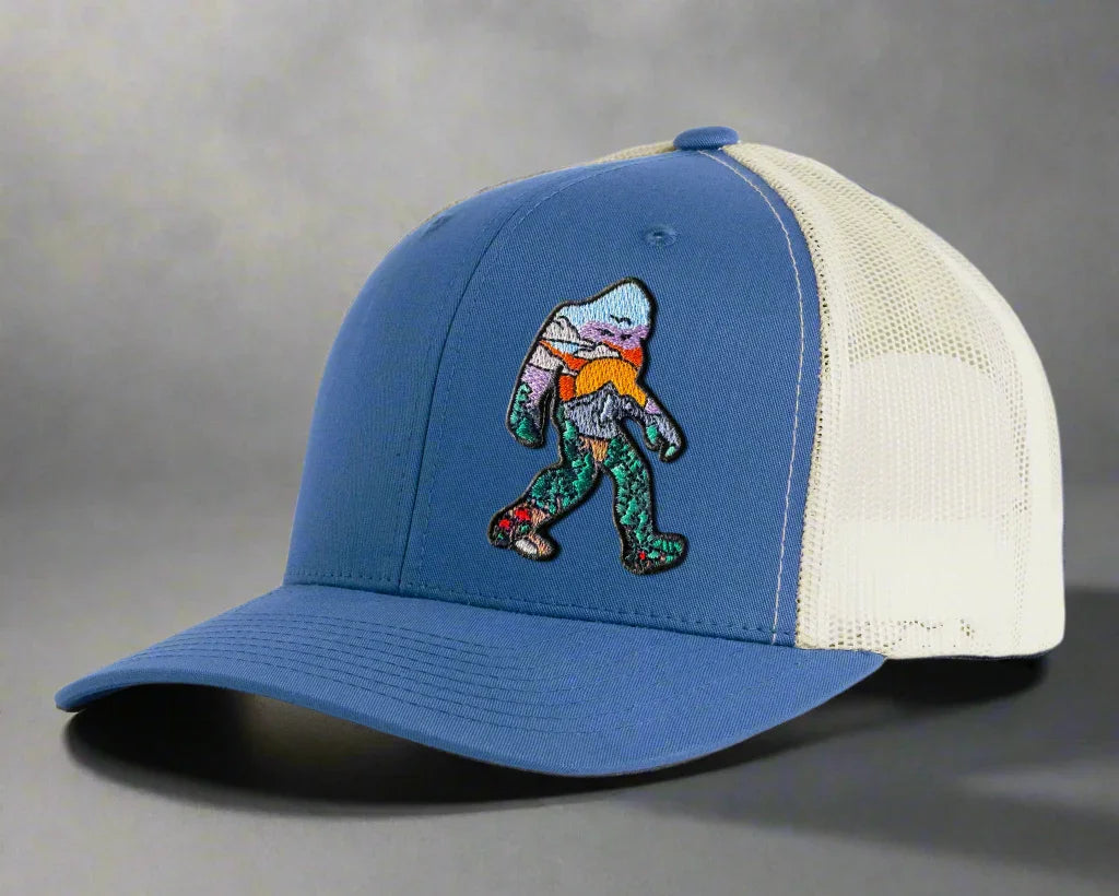 Blue and white mesh trucker hat with colorful Sasquatch embroidery on front panel