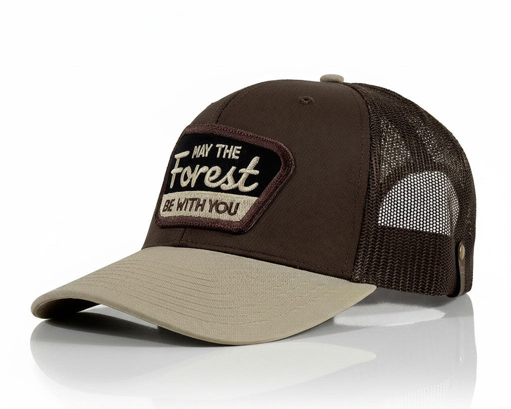 A dark brown and khaki trucker hat with a mesh back and a front patch reading 'May the Forest Be With You'.