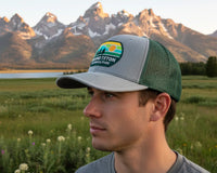 Person wearing a National Park Foundation cap with mountains in the background