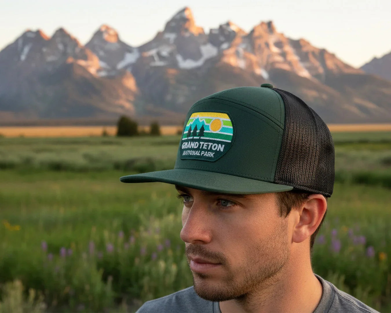 Man wearing a Grand Teton National Park cap with mountains in the background