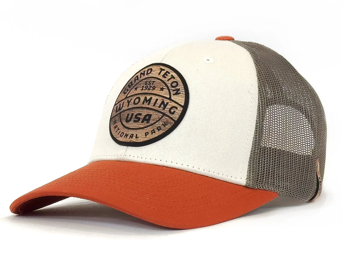 Trucker hat with white front panel, orange bill, and mesh back on a white background