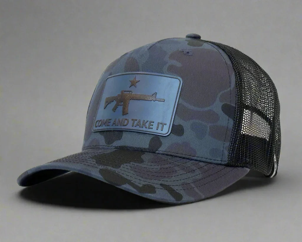 Camouflage cap with a patch featuring an rifle and 'COME AND TAKE IT' text on a gray background