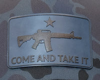 Metallic patch with gun design and 'COME AND TAKE IT' text on a camouflage background