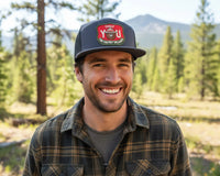 Man wearing a cap with a logo in a forest setting