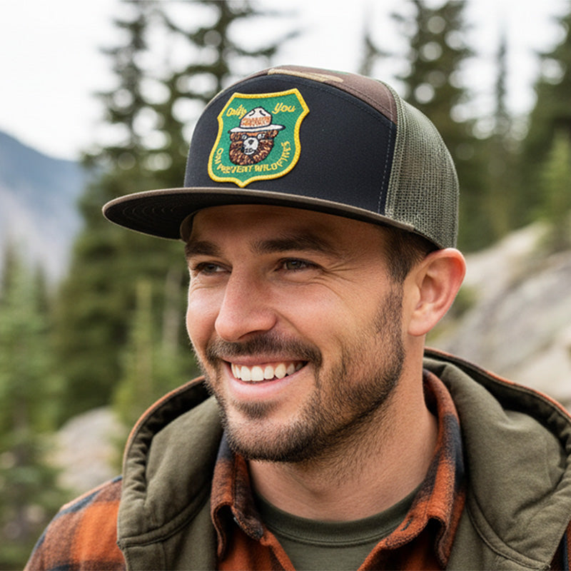 Man wearing a cap with a logo in a forest setting