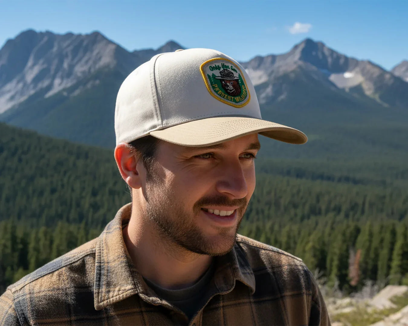 Man wearing a cap with a logo in front of mountainous landscape