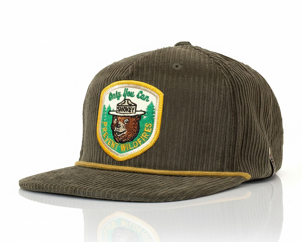 Green corduroy cap with a patch featuring a bear and text on a white background