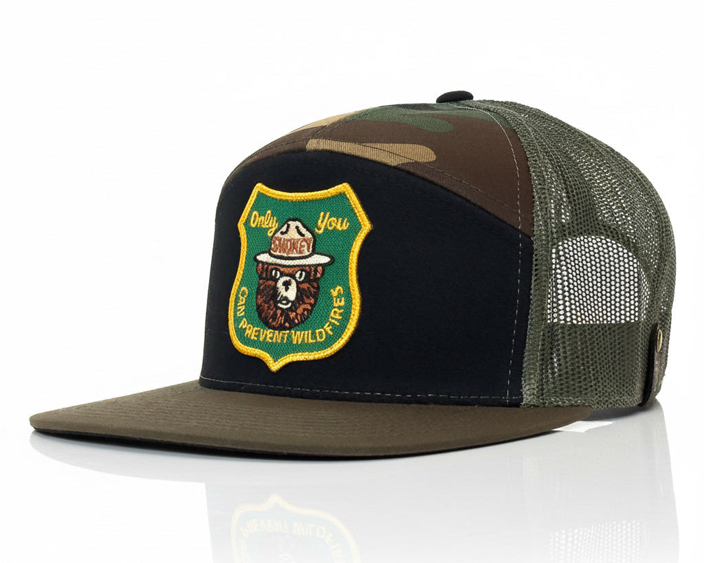 Camouflage and black trucker hat with a patch on a white background