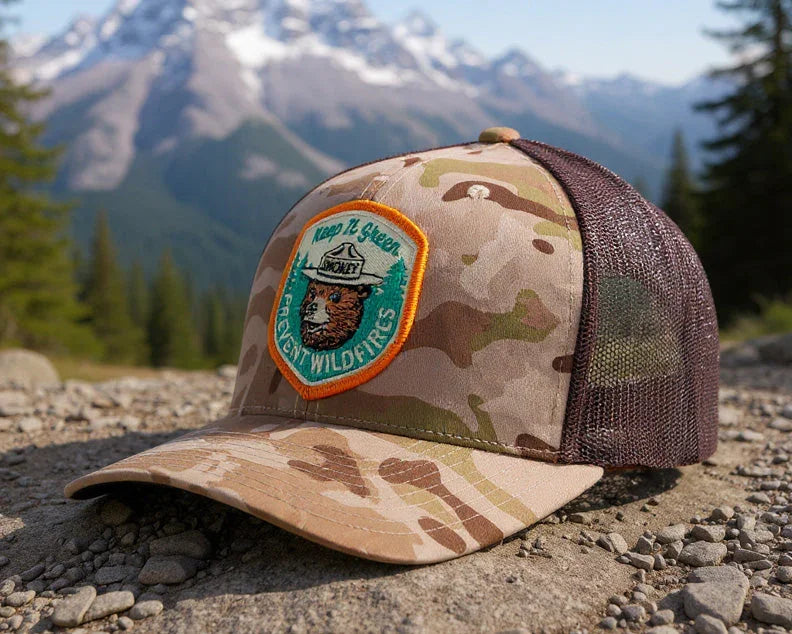 Camouflage cap with a patch on a rocky surface with mountains in the background