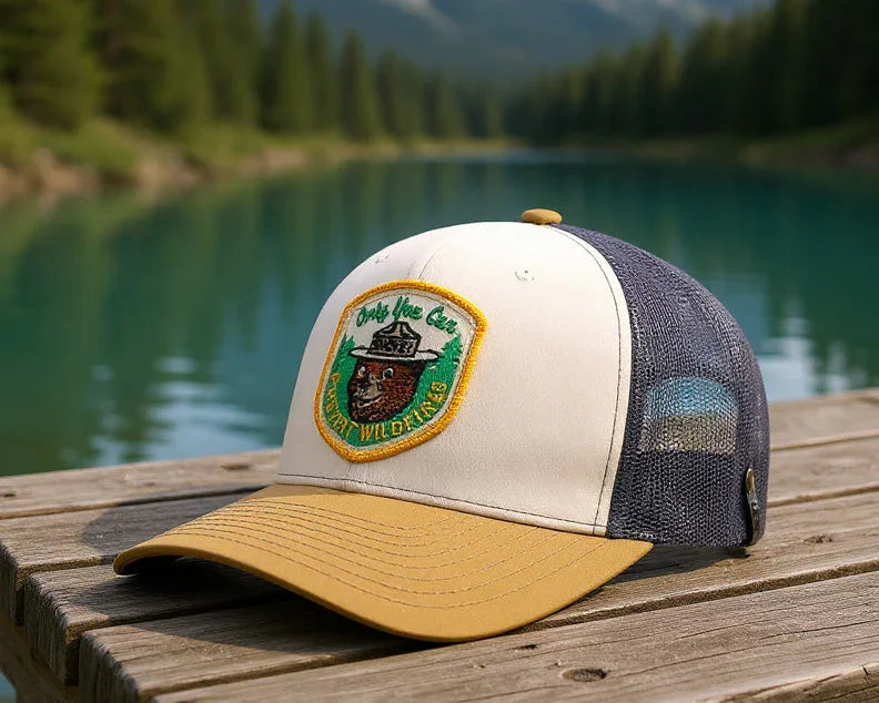 Cap with a logo on a wooden dock by a lake with mountains in the background