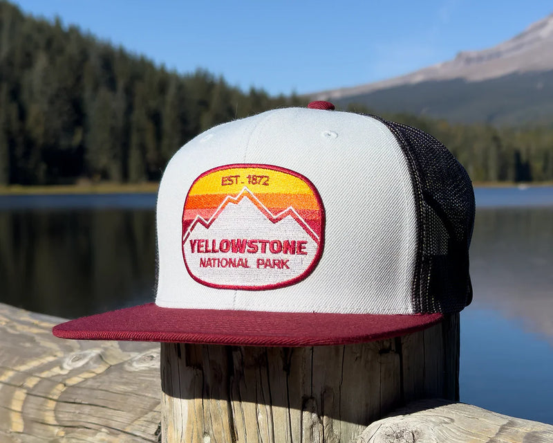 Yellowstone National Park cap on a wooden post with a lake and mountains in the background