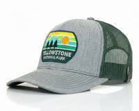 A heather gray and dark green trucker hat with a 'Yellowstone National Park' patch on the front, set against a clean white background with a subtle reflection.