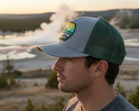 Person wearing a cap with a logo against a scenic background