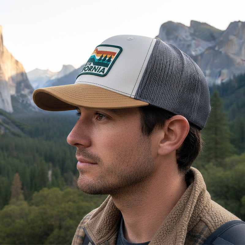Man wearing a cap with a logo against a mountainous landscape