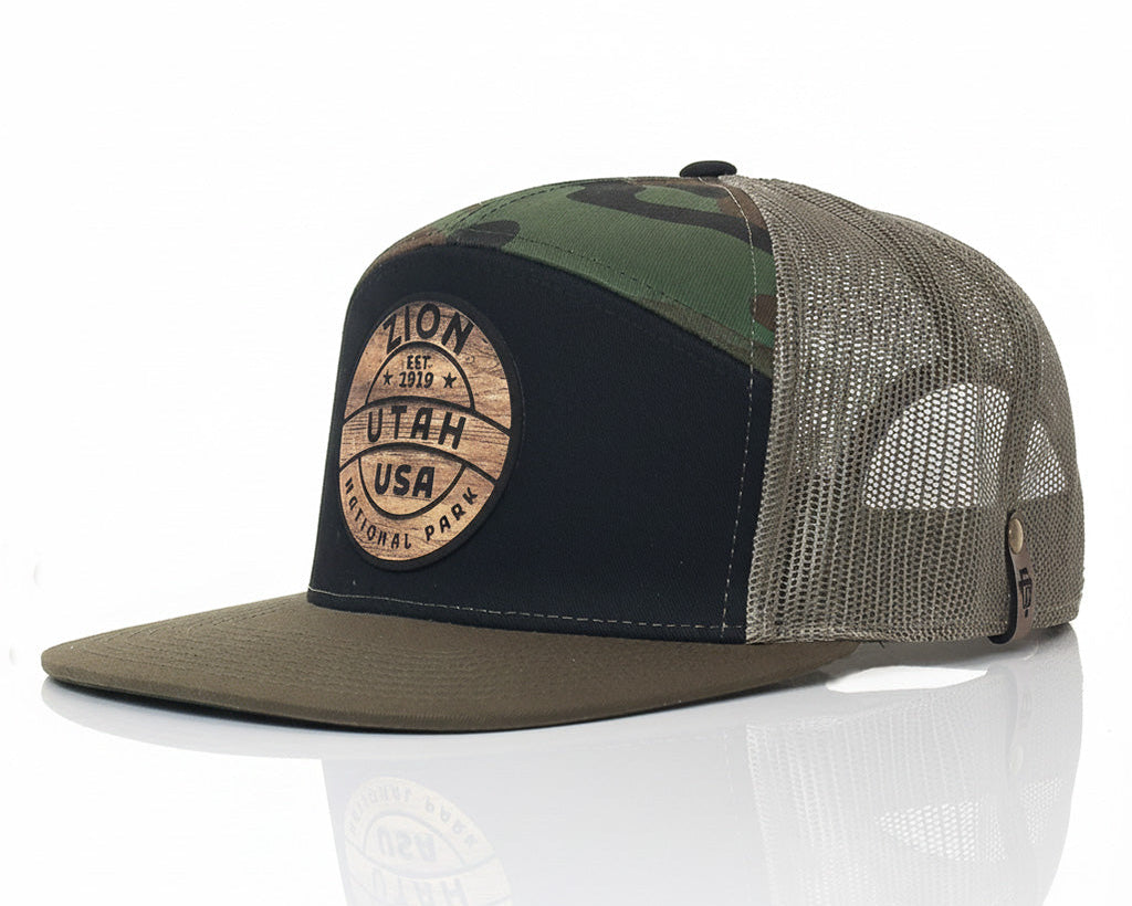 Camouflage and black trucker cap with a wooden patch on a white background