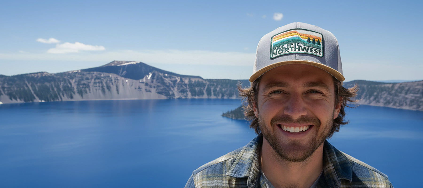 Person wearing a 'Northwest' cap with a scenic background of a lake and mountains.
