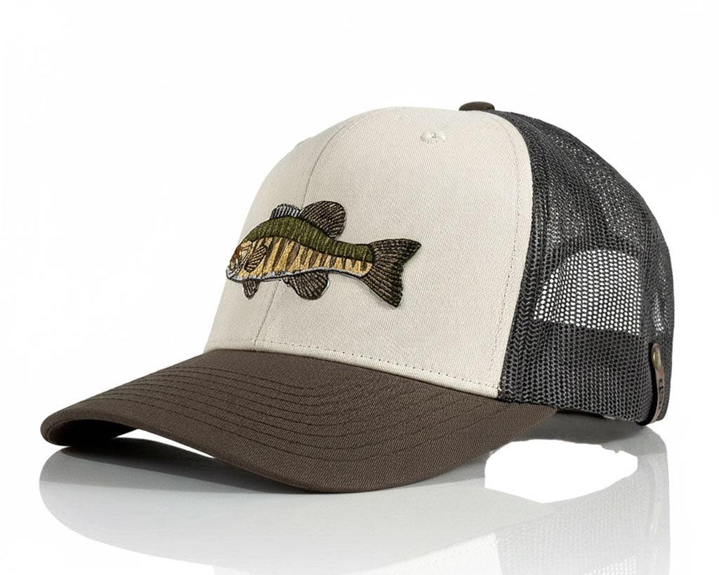 A trucker-style baseball cap with a cream front panel, dark brown visor, and black mesh back. The front panel features an embroidered fish design in green, brown, and black.